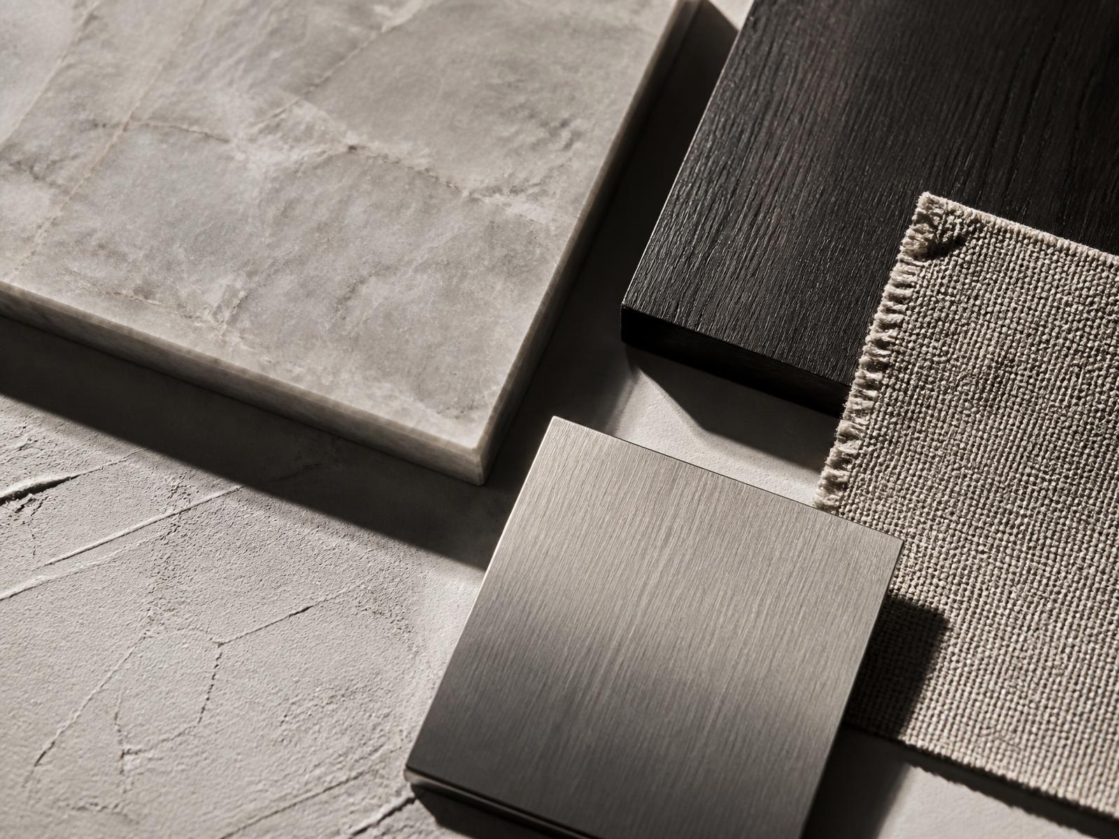 Stone, oak, brushed metal and linen samples arranged on a plaster surface